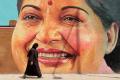 A woman walks past a huge portrait of late chief minister Jayalalithaa - Sakshi Post