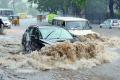 Vehicles  struggling through a flooded street in Hyderabad on Monday evening. - Sakshi Post