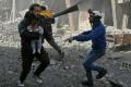 A Syrian man carries an infant injured in government bombing in the rebel-held town of Hamouria, in the besieged Eastern Ghouta region on the outskirts of the capital Damascus, on Monday - Sakshi Post