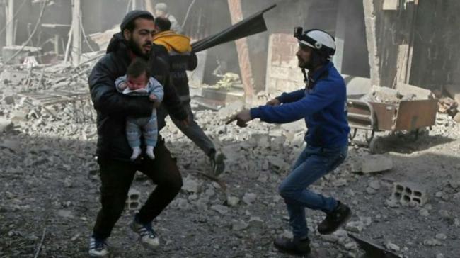 A Syrian man carries an infant injured in government bombing in the rebel-held town of Hamouria, in the besieged Eastern Ghouta region on the outskirts of the capital Damascus, on Monday - Sakshi Post